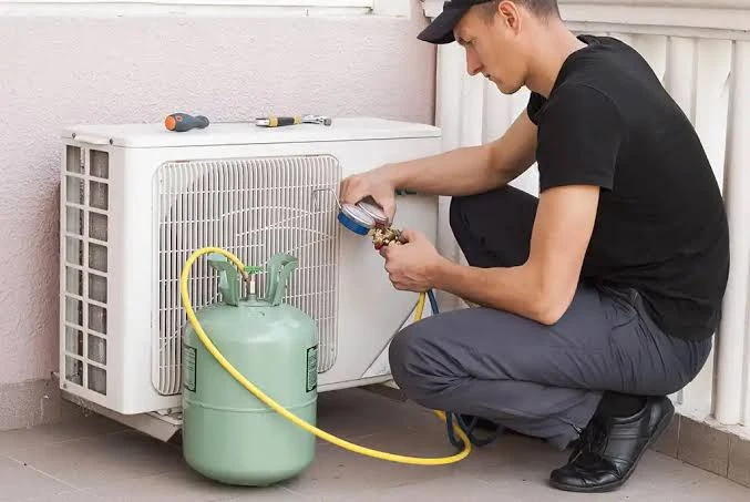 Technician using service gauges beside a residential outdoor cooling unit