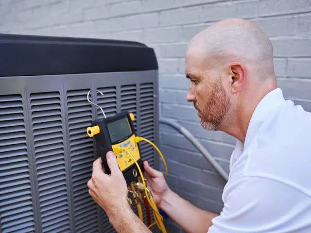 Technician using a handheld diagnostic meter to check HVAC equipment